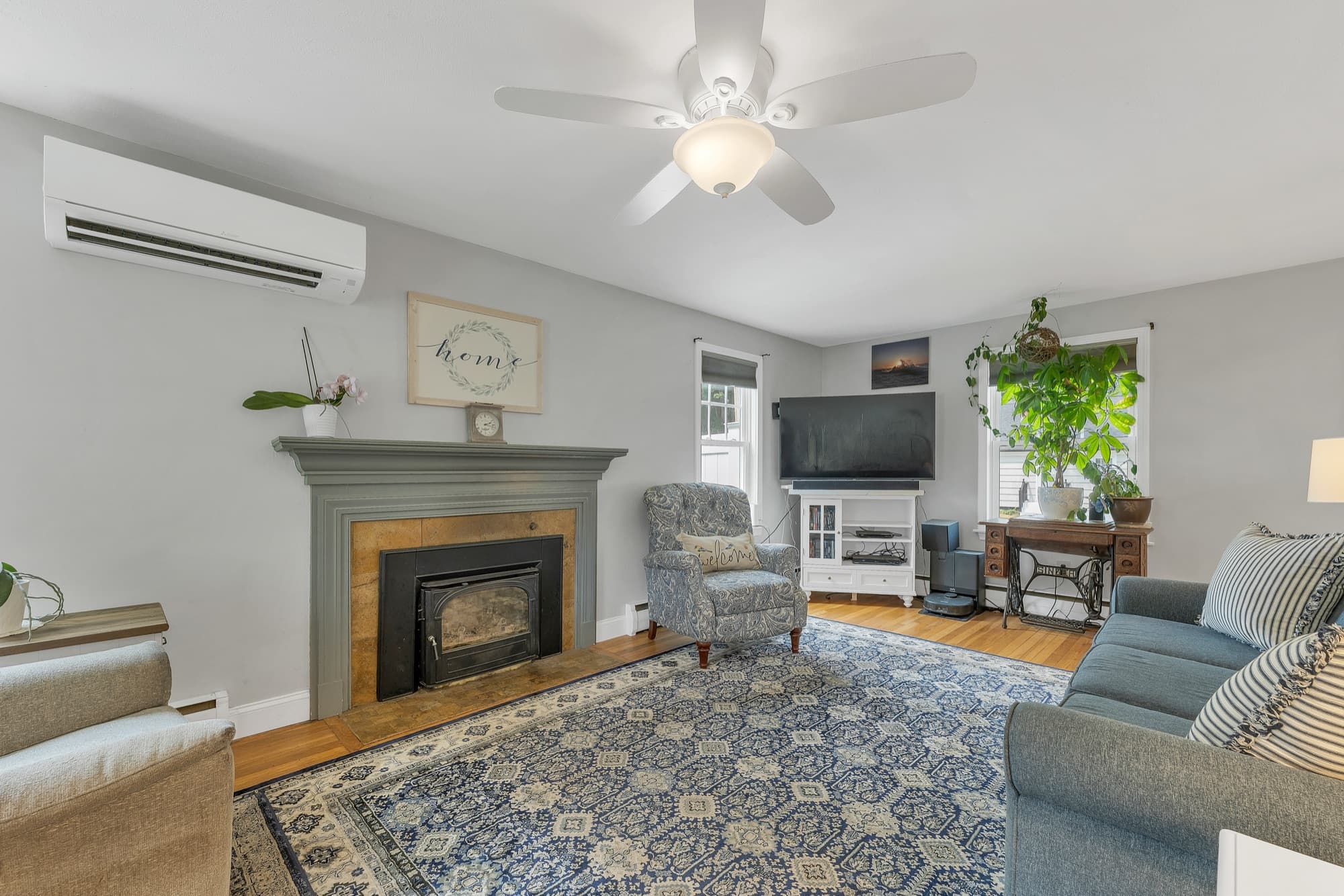 Living room with the fireplace and painted mantel, and a wall-mounted mini split at left