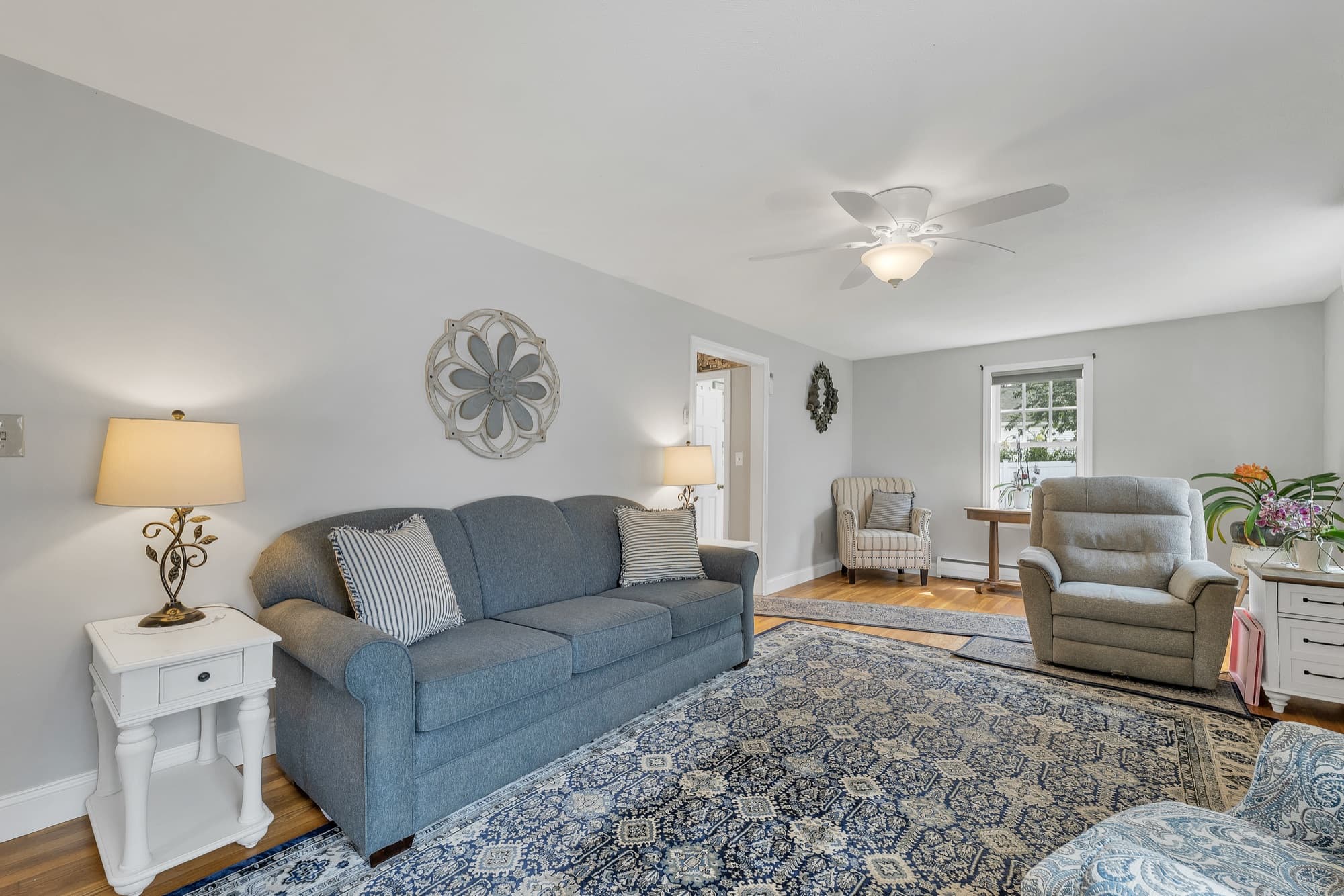 Living room with hardwood floors, a ceiling fan, and windows on two sides