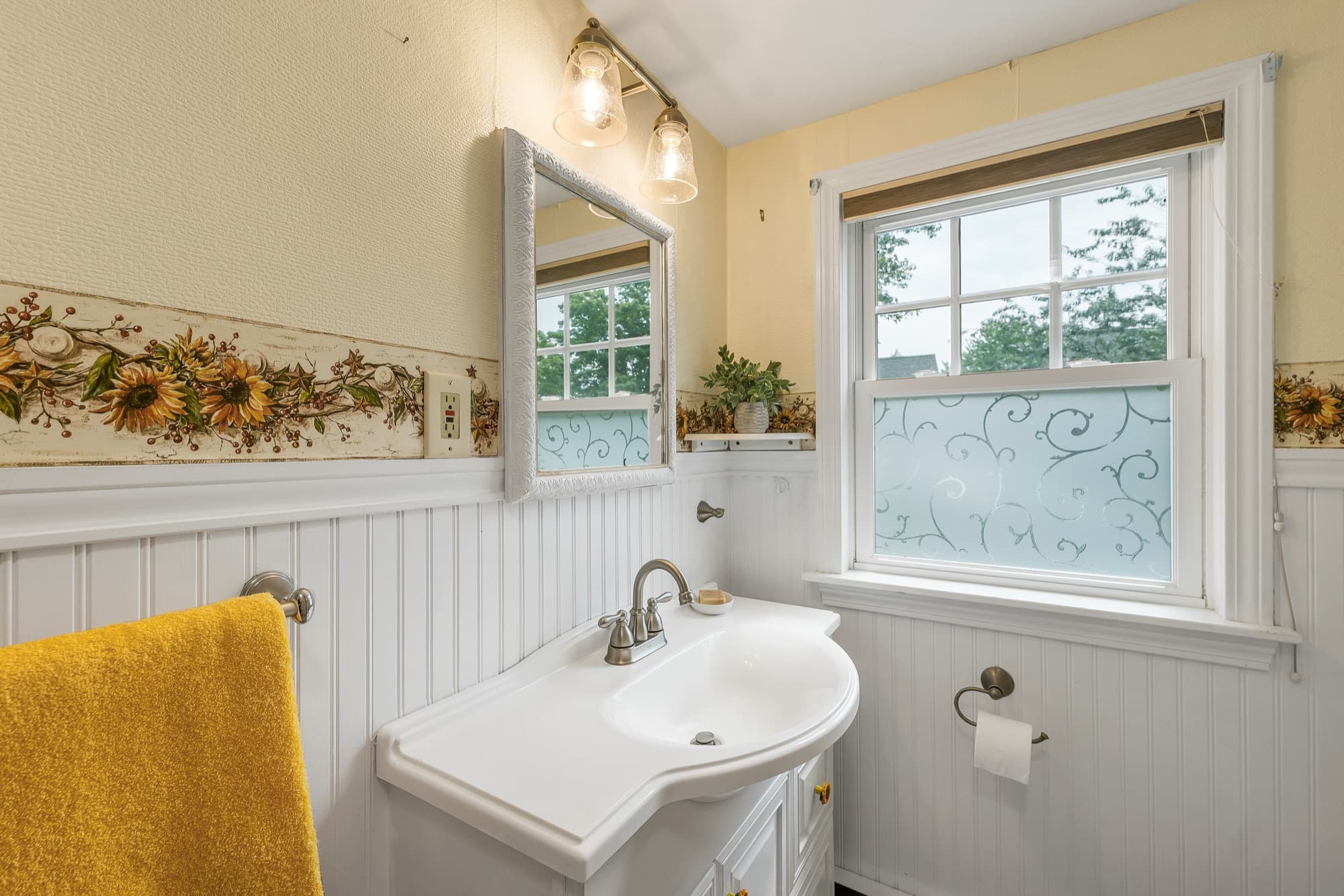 Second-floor full bath with beadboard wainscot and a window
