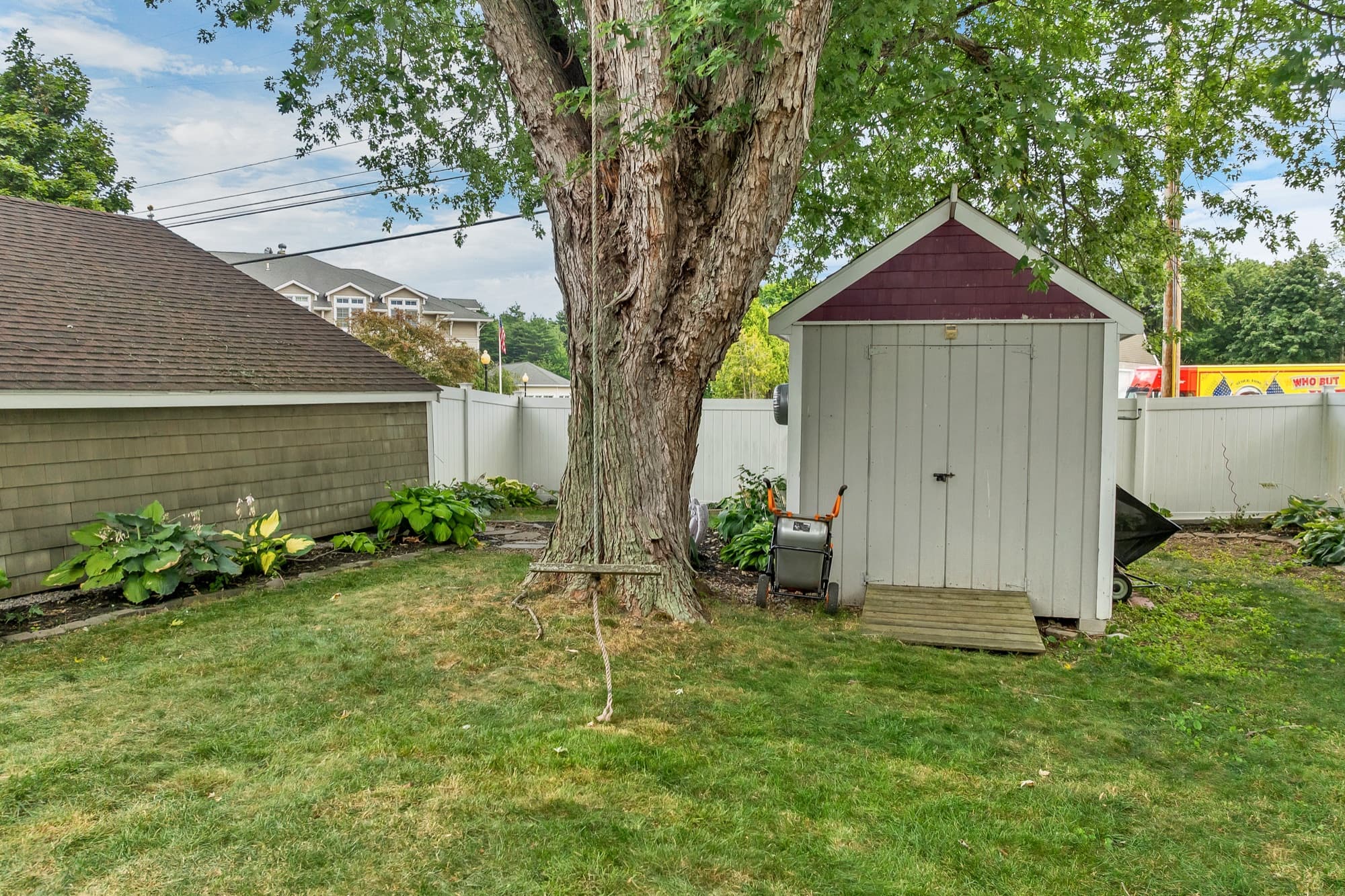 Storage shed beside a mature shade tree in the fenced backyard